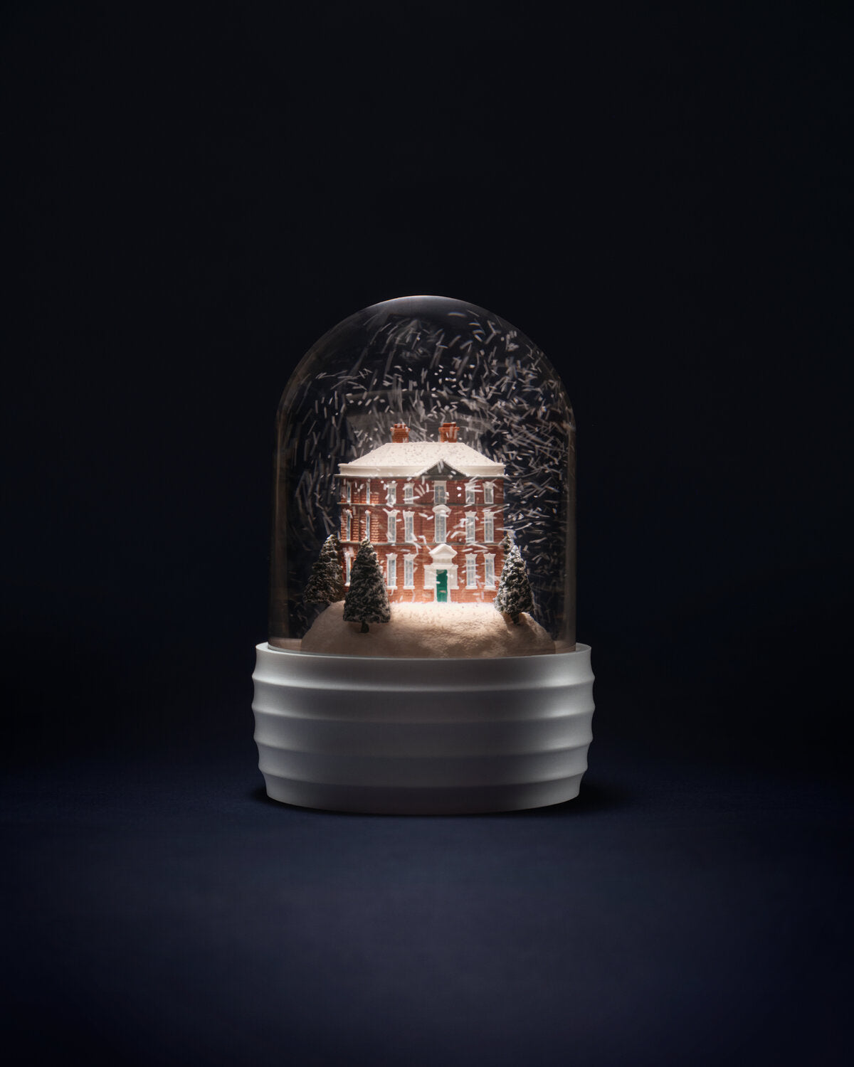 A decorative Wedgwood annual snow globe-style night light featuring a miniature illuminated wedgwood house scene under a clear dome, set on a ribbed white base against a dark studio background.