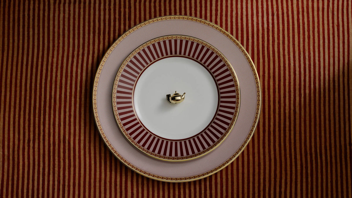 Stack of three red splendour decorative plates with red, white, and gold patterns, set against a red and gold striped background.